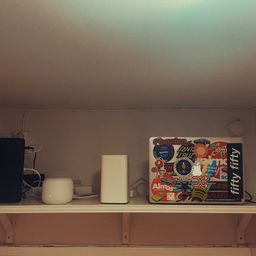 Wooden shelf above a door with a modem, router, NAS, and laptop.